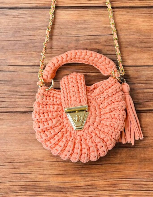 Pink woven handbag with a gold clasp on a wooden surface